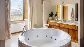 Un bagno moderno con una grande vasca, un mobile contenitore in legno e un ampio specchio.