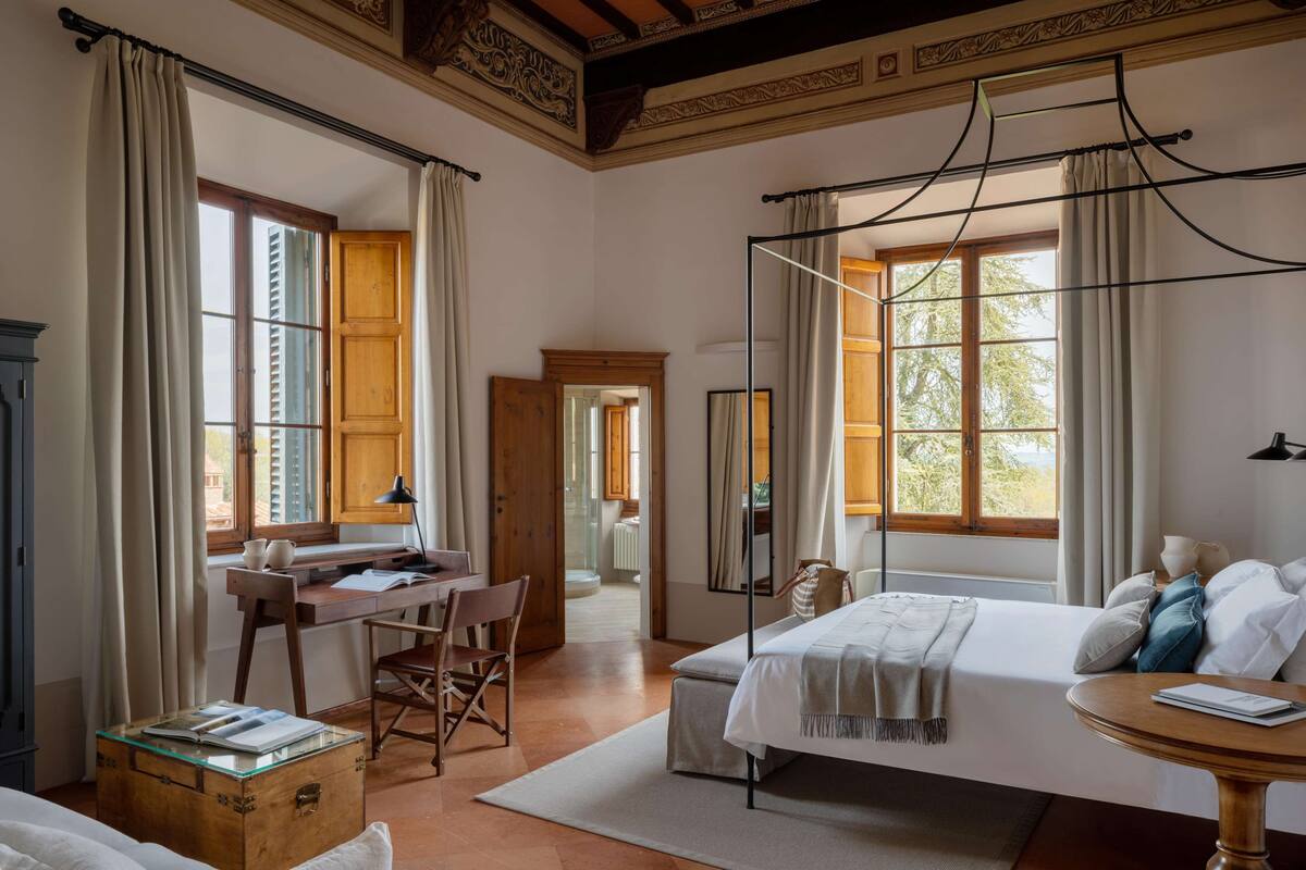 Ein Schlafzimmer mit Bett, Schreibtisch, Stuhl und einem großen Fenster.