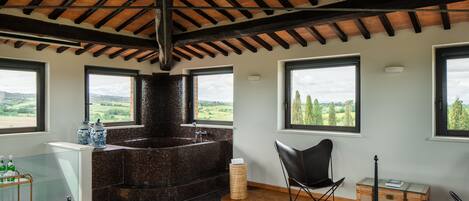 A modern bathroom with a freestanding bathtub, large windows, and a view of the countryside.
