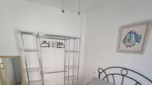 A bedroom with a bed, a metal headboard, a wall-mounted shelf unit, and a framed picture. - 600m de la Playa, Terraza Soleada (Salobreña)