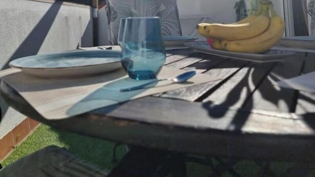 A patio table with a glass, a banana, and a vase of flowers. - 600m de la Playa, Terraza Soleada (Salobreña)