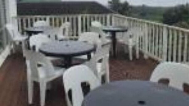 A deck with white plastic chairs and tables, overlooking a landscape. - Beachfront Inn (Winterstrand)