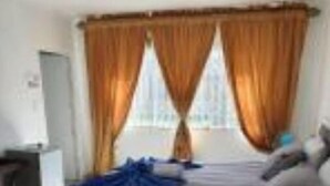 A bedroom with a bed, curtains, a desk, and a chair. - Beachfront Inn (Winterstrand)