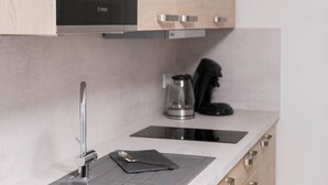 A kitchen with a Bosch microwave, a coffee maker, a sink with a faucet, and a countertop with a checkered towel. - Comfort apartment no. 1 on the first floor on the right (street side, without terrace) (Dormagen)