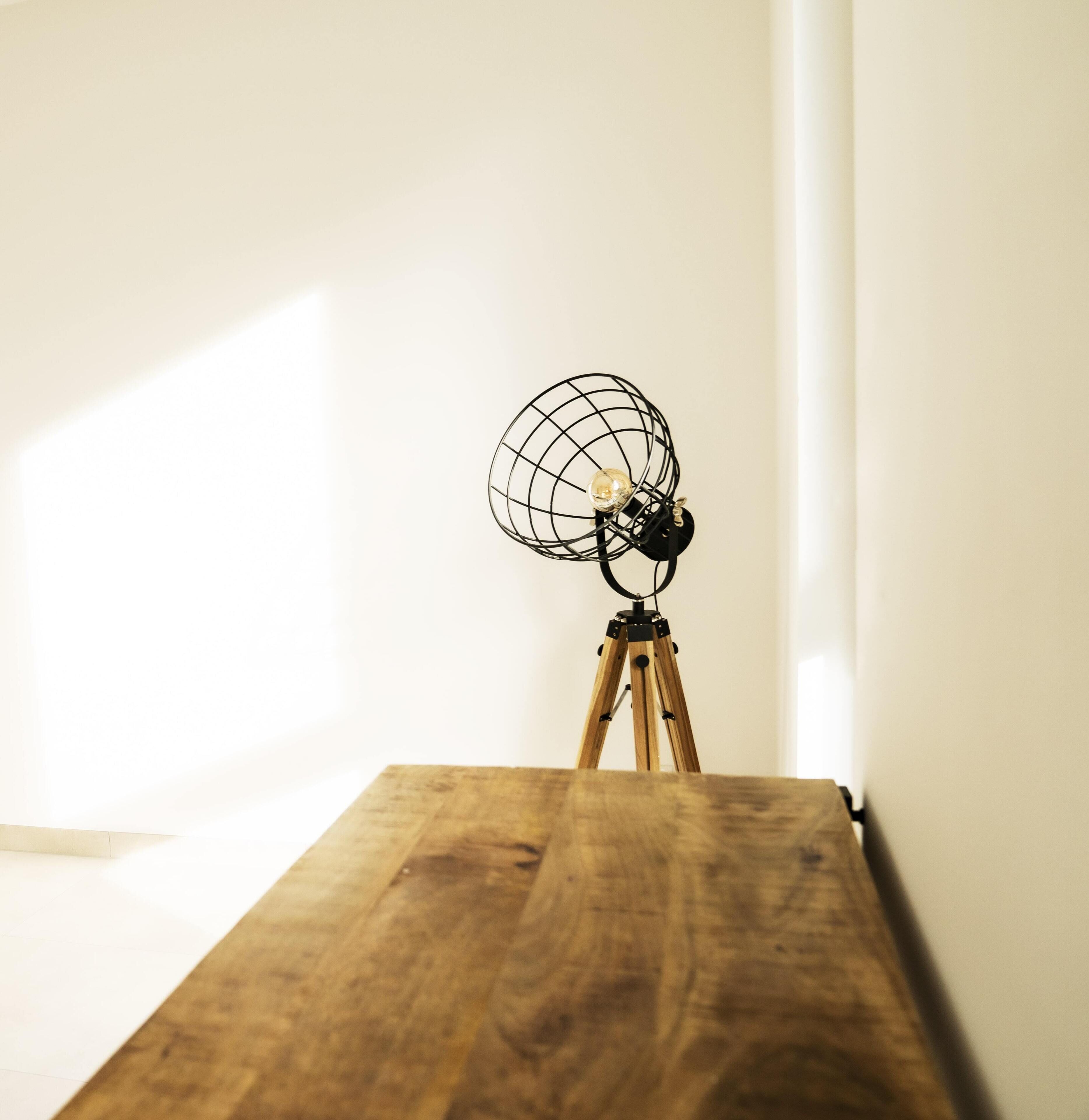 Un cavalletto in legno con una lampada a sfera in fil di ferro sopra.