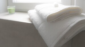 A stack of white towels on a window sill with a green container in the background. - Penthouse apartment no. 10 on the 2nd floor on the right (garden view, large roof terrace) (Dormagen)