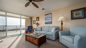 A living room with a light blue sofa, a wooden coffee table with a toy car, a floor lamp, and a ceiling fan.