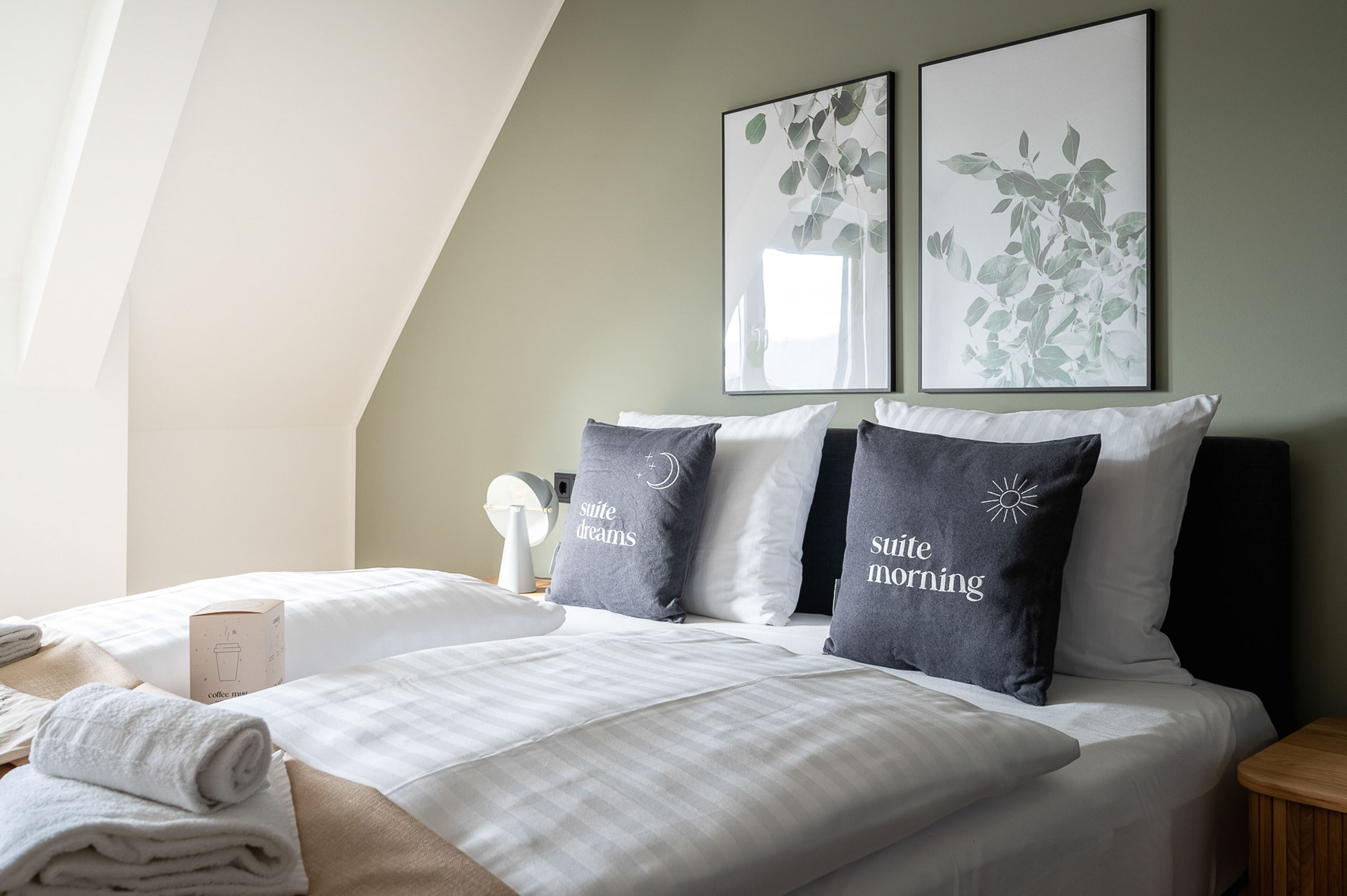 A hotel room with two beds, a coffee machine, and artwork on the walls.
