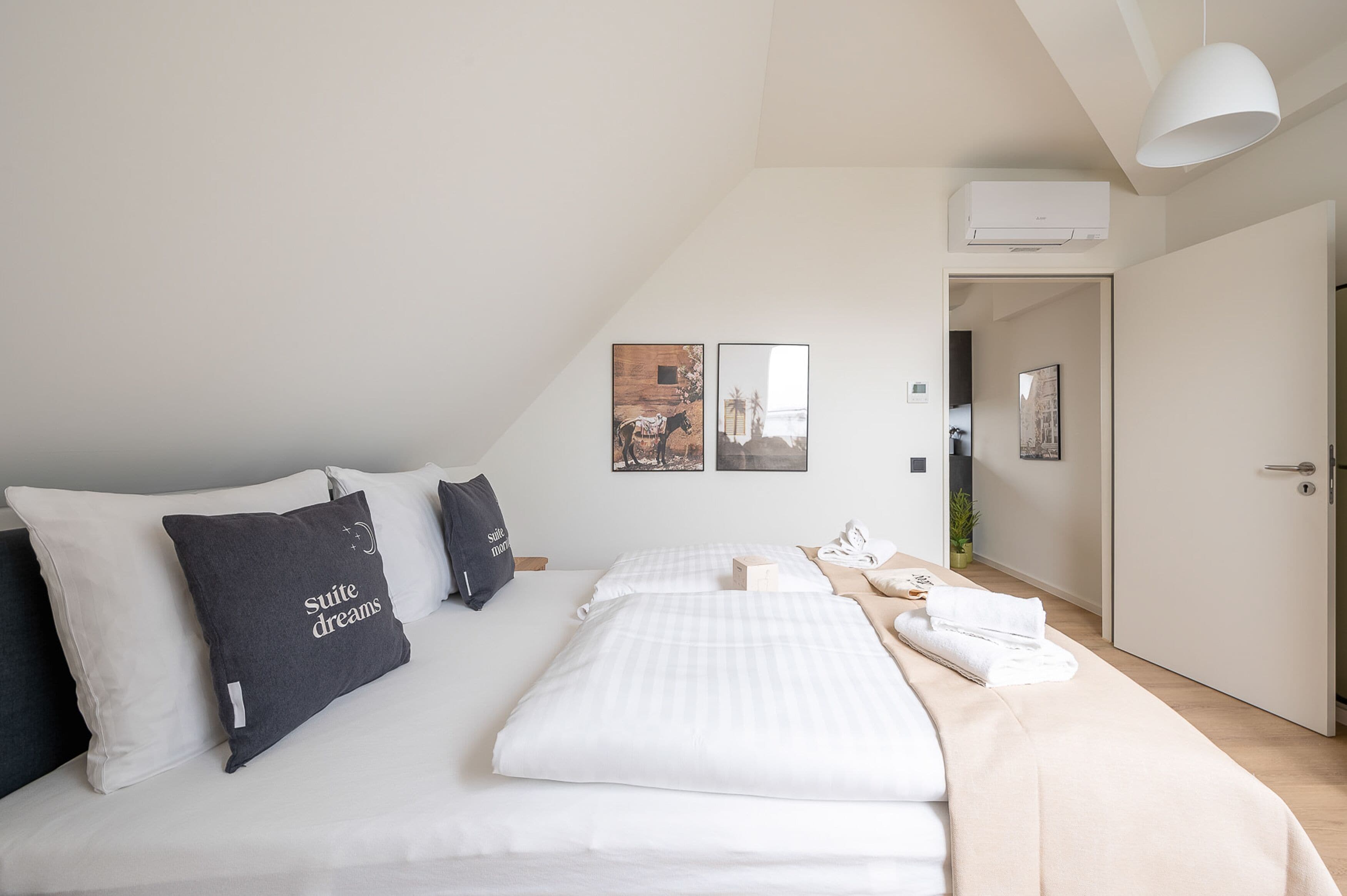 Habitació d'hotel moderna amb un llit ben fet, un finestral gran i una porta que dóna a un passadís.