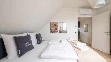 Una habitación de hotel moderna con una cama bien hecha, un ventanal grande y una puerta que da a un pasillo.