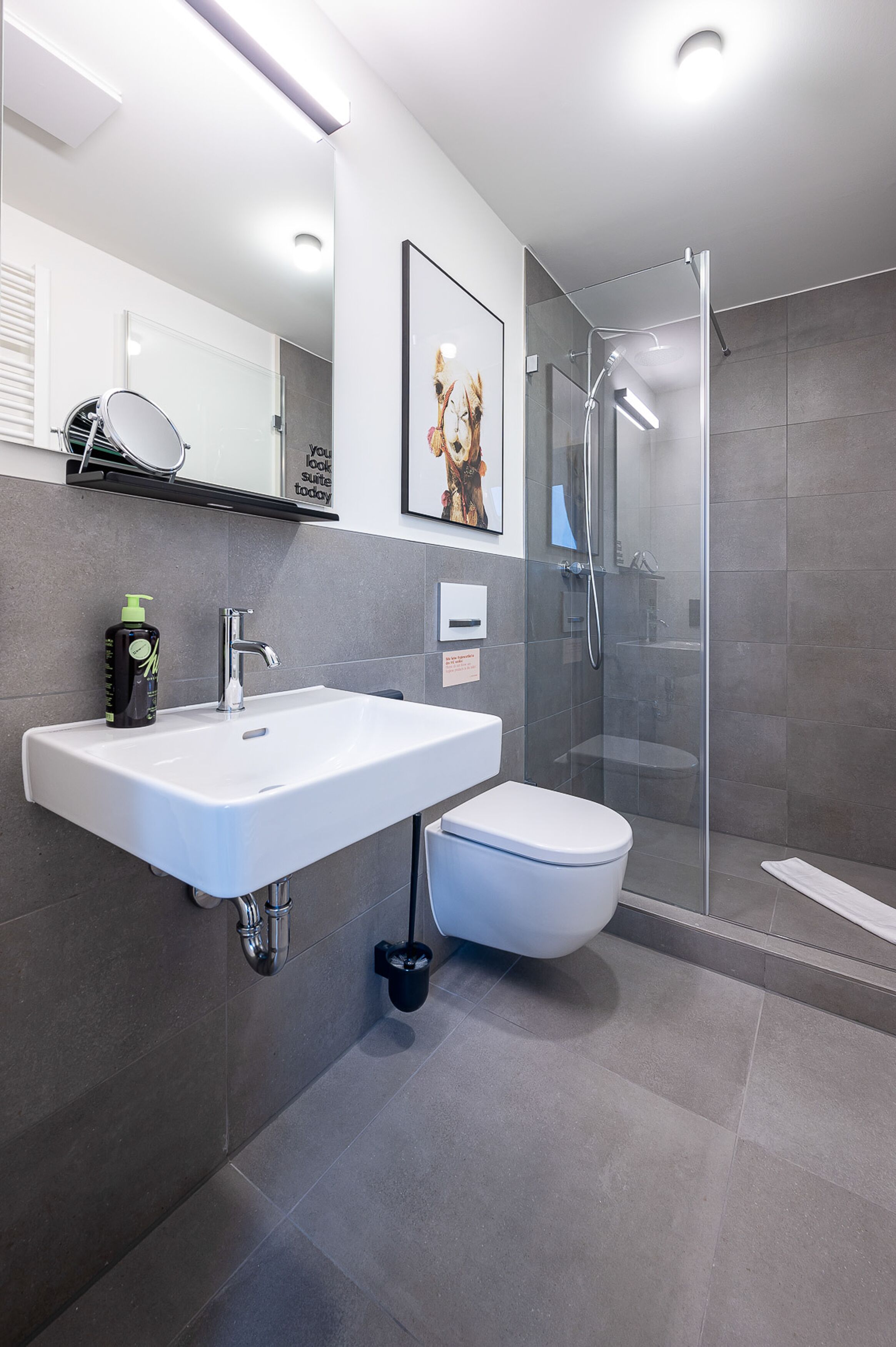 Une salle de bain moderne avec un lavabo blanc, des toilettes et une douche à parois de verre.