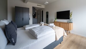 A modern bedroom with a large bed, a wooden dresser, a TV, and a mirror. - Limehome Stuttgart Elsenhansstr. (Stuttgart)