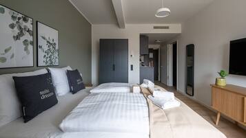 A modern hotel room with a large bed, a wooden console table, and a flat-screen TV mounted on the wall.