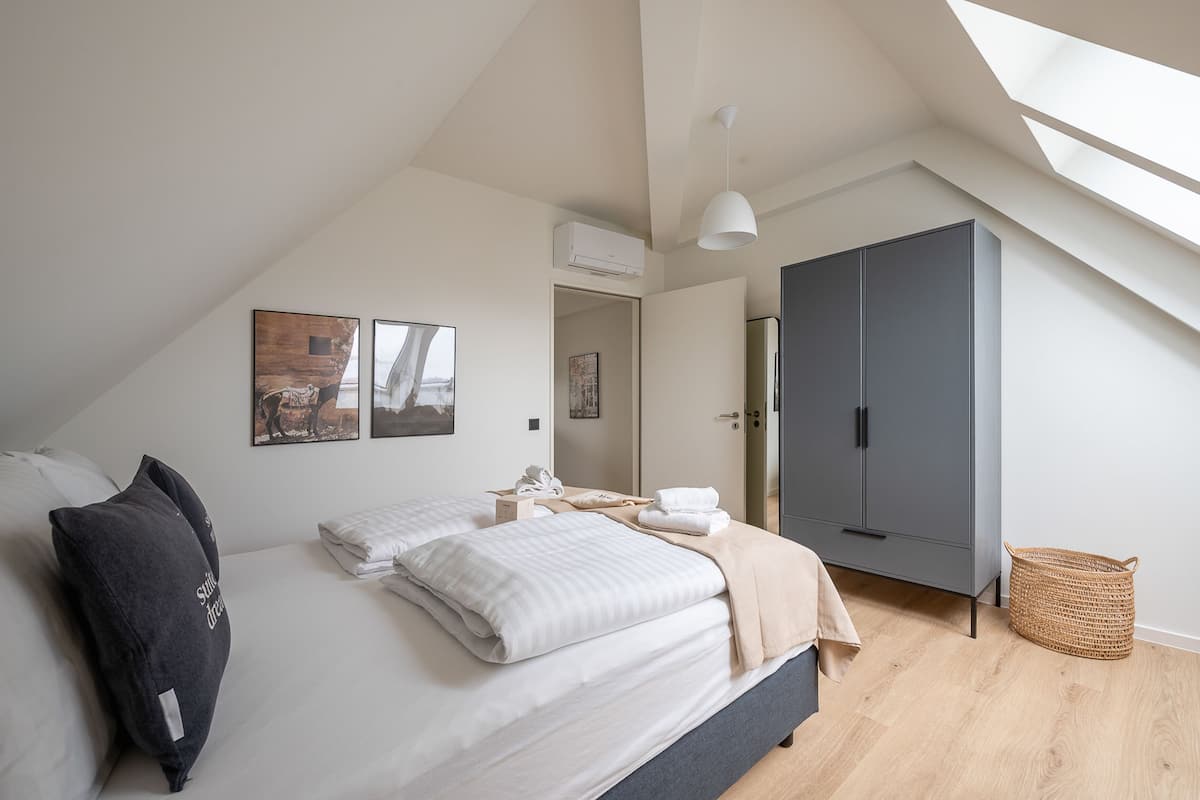 A bedroom with a bed, a wardrobe, a hanging light, and a skylight.