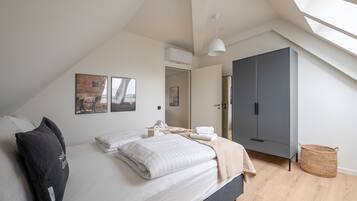 Un dormitorio con cama, armario, lámpara colgante y tragaluz.