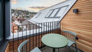 Un balcone con tavolo e sedie, vista su una città e rivestimento in legno alla parete.