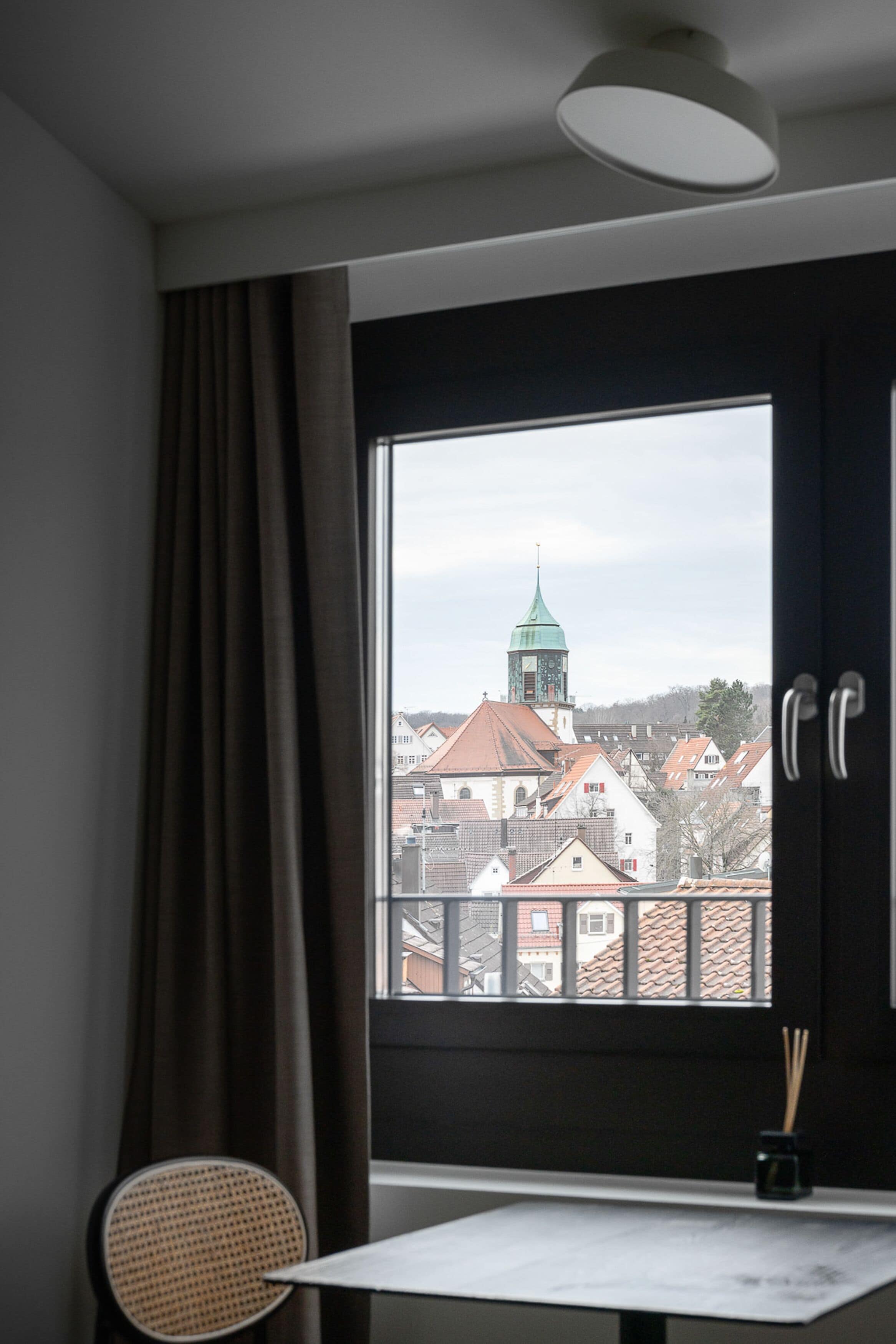A room with a large window, a chair, and a small table.