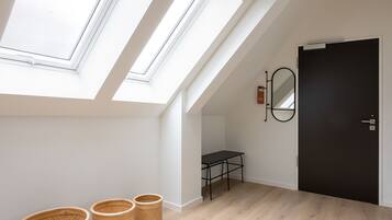 A room with skylights, a dark door, a small table, and three wicker baskets.