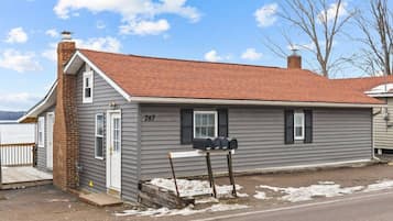 A single-story house with a gray siding exterior, a red-tiled roof, and a mailbox on the front.
