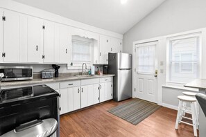 A modern kitchen with white cabinets, stainless steel appliances, and a wooden floor. - 2BR Camp w/ Amazing Beach Views (Colchester)