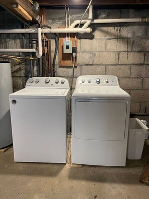 Two front-loading washing machines in a utility room with exposed pipes and a wooden beam above. - 2BR Camp w/ Amazing Beach Views (Colchester)