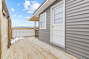 A wooden deck with a view of the ocean, a covered area, and a garage door. - 2BR Camp w/ Amazing Beach Views (Colchester)