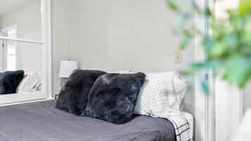 A bedroom with a bed, a large mirror, and a potted plant.