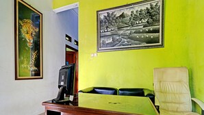 Un comptoir d’accueil avec un écran d’ordinateur, une chaise et deux tableaux encadrés accrochés au mur.