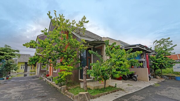 Une maison d’habitation avec un porche, un petit jardin et une allée pavée.