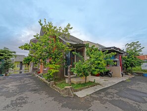 Ein Wohnhaus mit Veranda, kleinem Garten und befestigter Auffahrt.