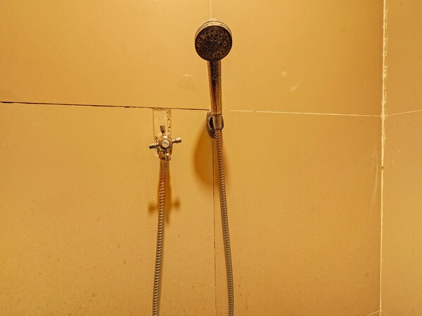 Eine Dusche mit Handbrause und Kopfbrause, beide an einem wandmontierten Bedienventil befestigt.