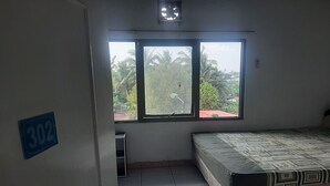 Een kamer met een bed, een raam met uitzicht op palmbomen en een deur met een nummerbord.