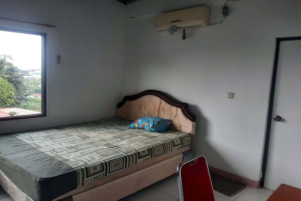 Una habitación pequeña con una cama individual, una ventana y una puerta.