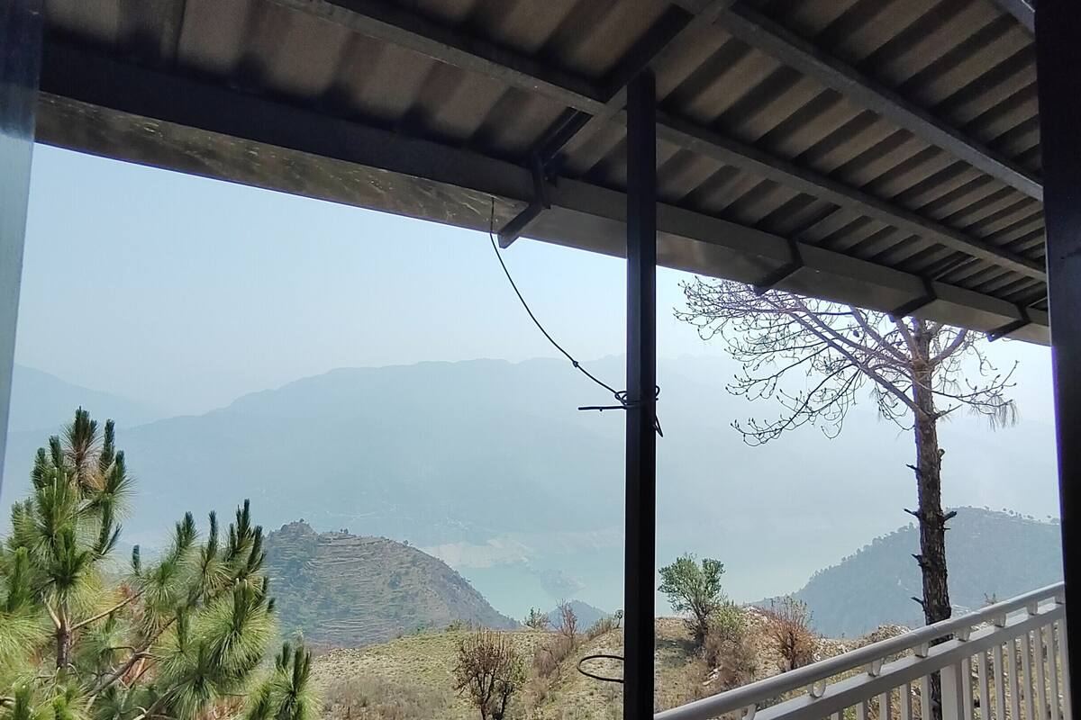 A covered outdoor area with a view of mountains and a lake.