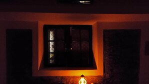 A dimly lit room with a window and a wall-mounted lantern. - Atulya Neer Hotel  (Tehri)