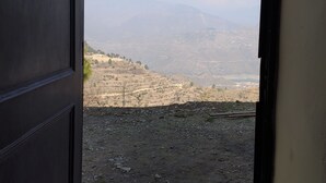 A view from inside a building, looking out at a mountainous landscape with a clear sky. - Atulya Neer Hotel  (Tehri)