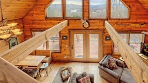 Uma cabana com quarto no mezanino, sala de jantar e sala de estar com lareira.