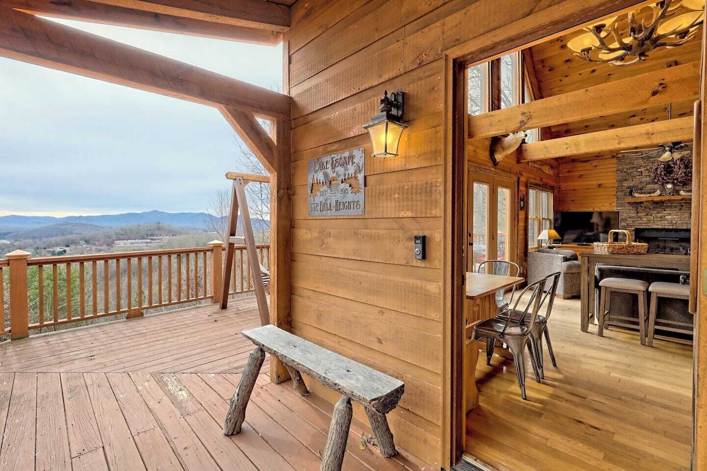 Eine Holzhütte mit einer Veranda, einer Bank, einem Schild mit der Aufschrift 'Lake Escape 512 Bell Heights' und Blick auf die Berge.
