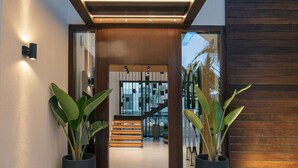 Una entrada moderna con techo de madera y puerta de cristal que da a una zona de recepción.