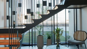 Un interior moderno con una escalera, una mesa redonda con una planta y una silla.