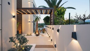 Un patio moderno al aire libre con pérgola, una palmera y un área de estar.
