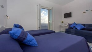A hotel room with two beds, a sofa, a small table, and a TV on the wall. - Domus Teresia - Amalfi Coast (San Michele)