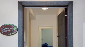 A hallway with a patterned floor, a door on the right, and a bed in the background. - Domus Teresia - Amalfi Coast (San Michele)