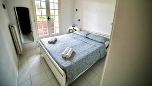 A bedroom with a bed, a window, a radiator, and a nightstand with a lamp. - [ZONA POETI] ★★★★★ Relax in Piscina - Free Parking (Loano)