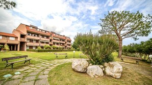 A courtyard with a stone pathway, benches, a tree, and a multi-story building with balconies. - [ZONA POETI] ★★★★★ Relax in Piscina - Free Parking (Loano)