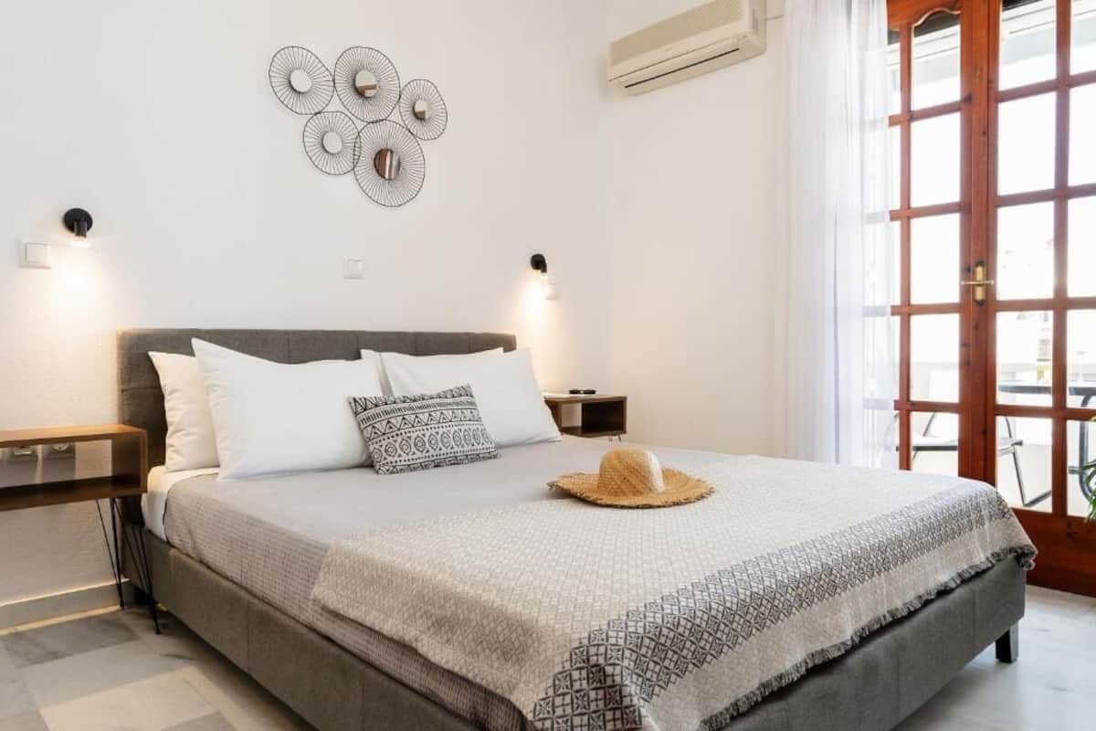 A neatly made bed with a patterned bedspread and a straw hat on it.