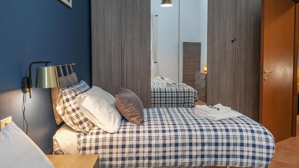 A bedroom with a bed, bedside tables, a lamp, and a wardrobe. - Rhome 14 Smart workers cozy apt (Rho)