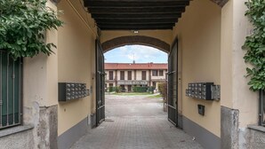 An arched entrance with mailboxes on either side, leading to a courtyard with a building in the background. - Rhome 14 Smart workers cozy apt (Rho)