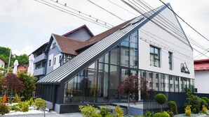 Un edificio moderno con techo inclinado, amplios ventanales y un jardín bien cuidado.