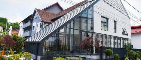 Un edificio moderno con techo inclinado, amplios ventanales y un jardín bien cuidado.